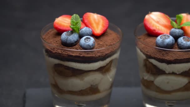 Dessert classique tiramisu aux myrtilles et fraises dans un verre sur plaque de service en pierre — Video