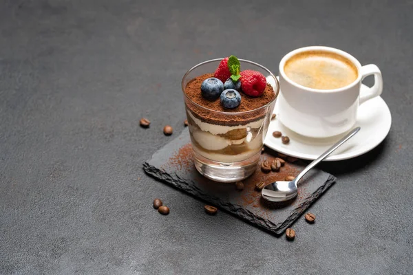 Tasse Kaffee klassisches Tiramisu-Dessert mit Blaubeeren und Himbeeren in einem Glas auf Steinplatte auf dunklem Betongrund — Stockfoto
