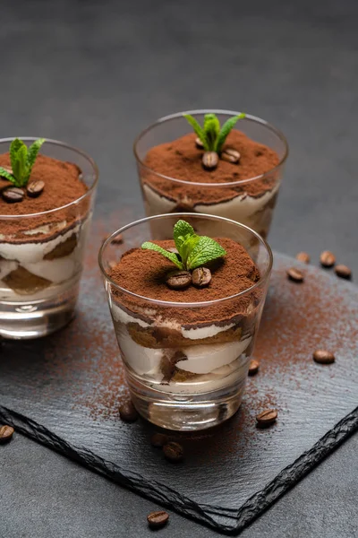 Sobremesa tiramisu clássico em um copo em pedra servindo placa no fundo de concreto escuro — Fotografia de Stock