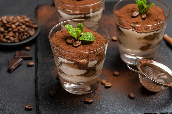 Postre tiramisú clásico en un vaso sobre tabla de servir de piedra sobre fondo de hormigón oscuro —  Fotos de Stock