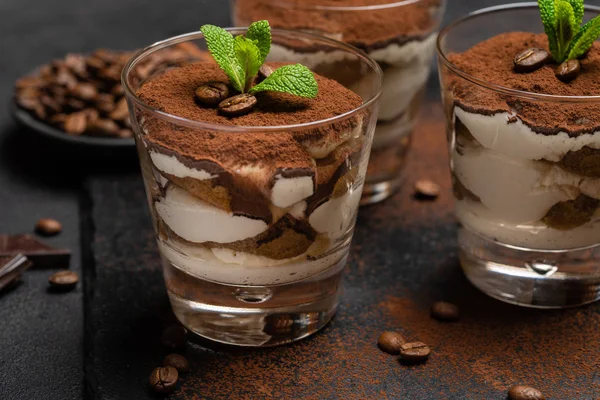 Postre tiramisú clásico en un vaso sobre tabla de servir de piedra sobre fondo de hormigón oscuro — Foto de Stock