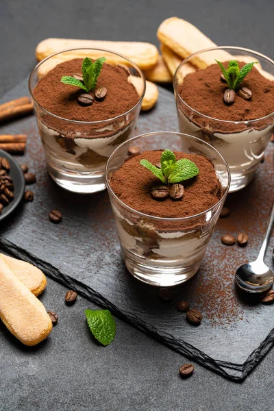 Classico dessert tiramisù in bicchiere e biscotti savoiardi su tavola da portata in pietra su fondo di cemento scuro — Foto Stock