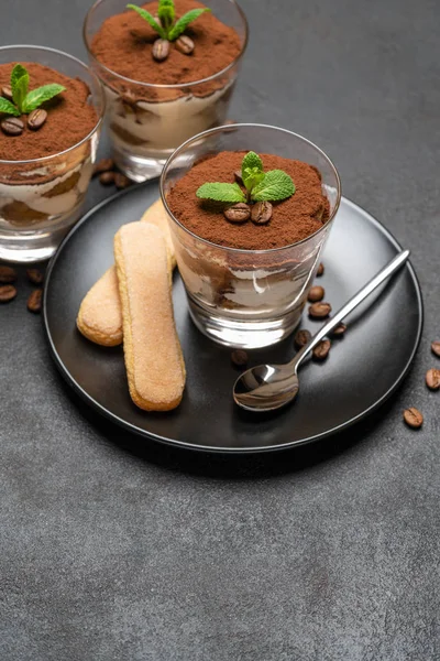 Klassisches Tiramisu-Dessert im Glas und savoiardi-Kekse auf dunklem Betongrund — Stockfoto