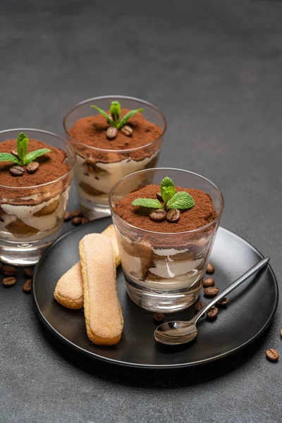 Classic tiramisu dessert in a glass and savoiardi cookies on dark concrete background — Stock Photo, Image