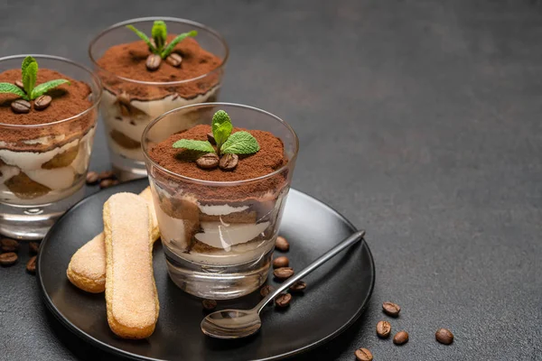 Sobremesa tiramisu clássica em um copo e biscoitos savoiardi no fundo de concreto escuro — Fotografia de Stock