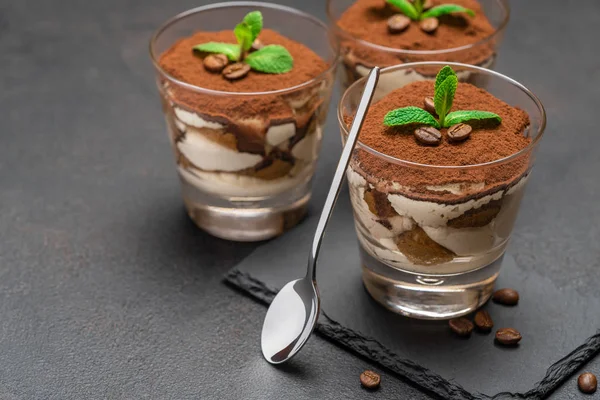 Sobremesa tiramisu clássico em um copo em pedra servindo placa no fundo de concreto escuro — Fotografia de Stock