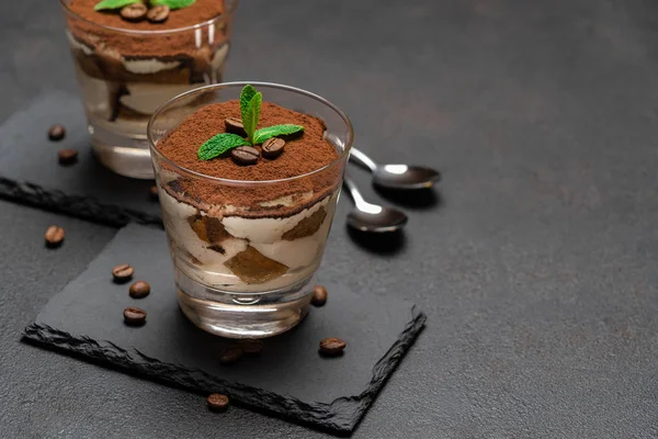 Classic tiramisu dessert in a glass on stone serving board on dark concrete background — Stock Photo, Image