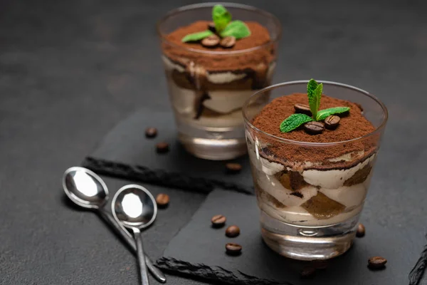 Postre tiramisú clásico en un vaso sobre tabla de servir de piedra sobre fondo de hormigón oscuro —  Fotos de Stock