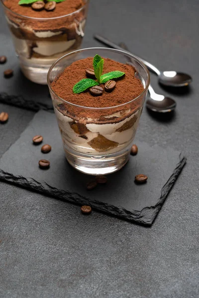 Sobremesa tiramisu clássico em um copo em pedra servindo placa no fundo de concreto escuro — Fotografia de Stock