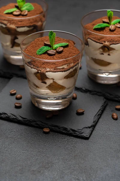 Postre tiramisú clásico en un vaso sobre tabla de servir de piedra sobre fondo de hormigón oscuro — Foto de Stock