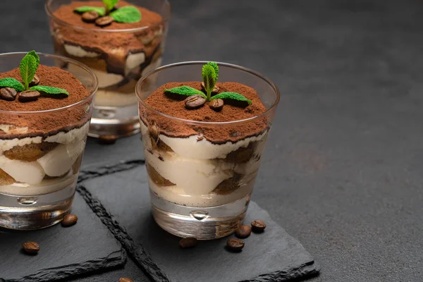 Classico dessert tiramisù in un bicchiere su tavola da portata in pietra su sfondo di cemento scuro — Foto Stock