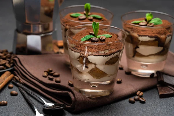 Sobremesa tiramisu clássico em um copo e cafeteira no fundo de concreto escuro — Fotografia de Stock