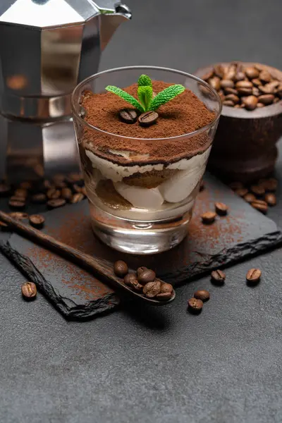 Klassisches Tiramisu-Dessert im Glas und Kaffeemaschine auf Steinplatte auf dunklem Betonhintergrund — Stockfoto