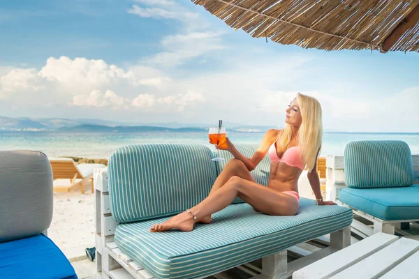 Mulher segurando Delicioso clássico gelado aperol spritz cocktail com cubos de gelo em uma praia tropical quente em sol de verão — Fotografia de Stock