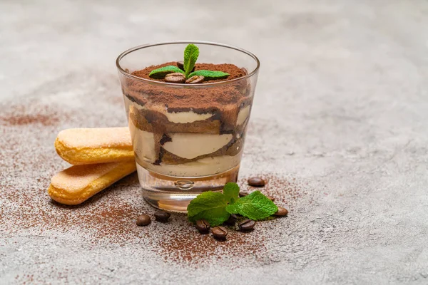 Postre tiramisú clásico en una taza de vidrio y galletas savoiardi sobre fondo de hormigón —  Fotos de Stock