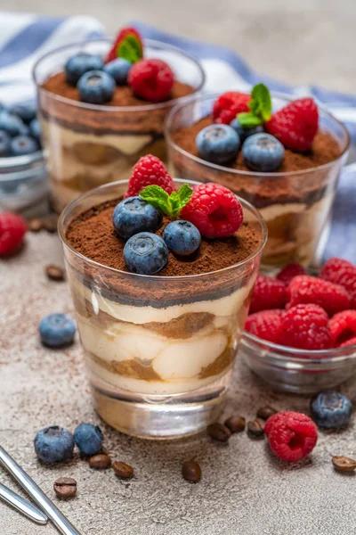 Sobremesa tiramisu clássica com mirtilos e framboesas em um copo e guardanapo no fundo de concreto — Fotografia de Stock