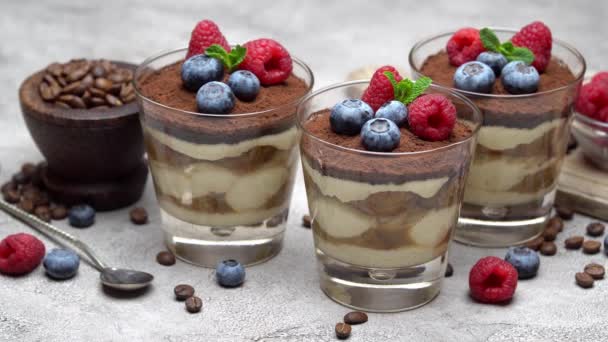 Klassisches Tiramisu-Dessert mit Blaubeeren und Himbeeren im Glas und Schalen mit Beeren — Stockvideo