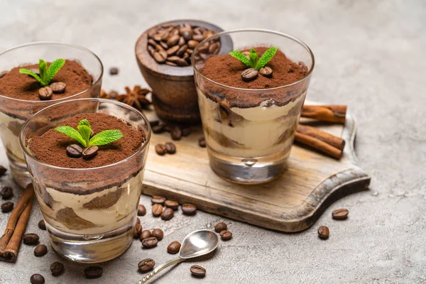 Postre tiramisú clásico en un vaso y palitos de canela sobre fondo de hormigón —  Fotos de Stock