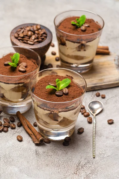 Sobremesa tiramisu clássico em um copo e paus de canela no fundo de concreto — Fotografia de Stock