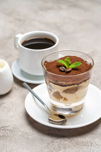 Dessert tiramisu classique dans un verre, tasse de café expresso et crème sur fond de béton — Photo