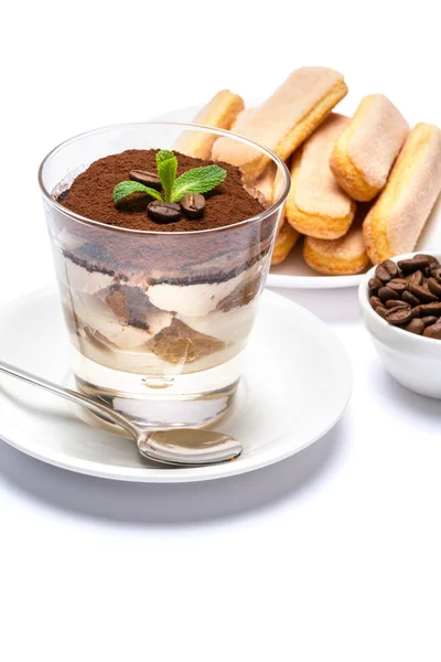 Postre tiramisú clásico en una taza de vidrio, galletas savoiardi y granos de café sobre fondo blanco con ruta de recorte —  Fotos de Stock