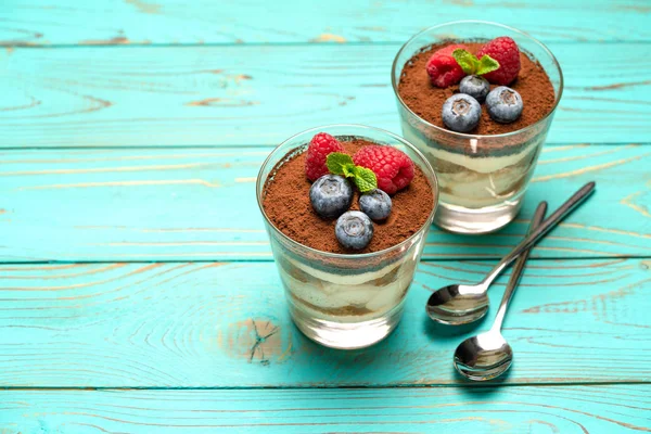 Klassiek Tiramisu-dessert met bosbessen en aardbeien in een glazen beker op houten achtergrond — Stockfoto