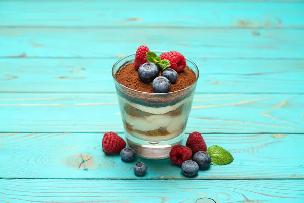 Klassisches Tiramisu-Dessert mit Blaubeeren und Erdbeeren in einer Glasschale auf Holzgrund — Stockfoto