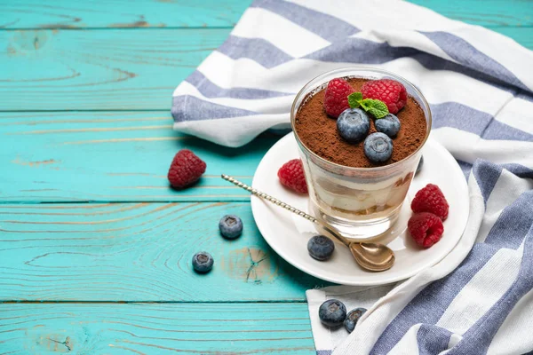 Klassiek Tiramisu-dessert met bosbessen en aardbeien in een glazen beker op houten achtergrond — Stockfoto