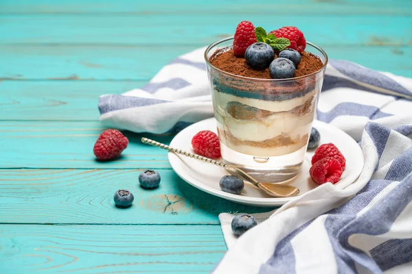 Klassiek Tiramisu-dessert met bosbessen en aardbeien in een glazen beker op houten achtergrond — Stockfoto