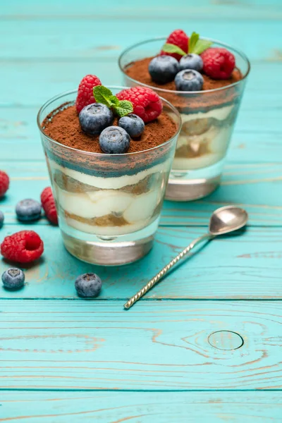 Klassiek Tiramisu-dessert met bosbessen en aardbeien in een glazen beker op houten achtergrond — Stockfoto