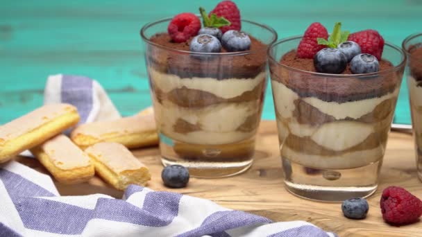 Klasyczny deser Tiramisu z jagodami i truskawkami w szklaną filiżankę i ciasteczka savoiardi — Wideo stockowe