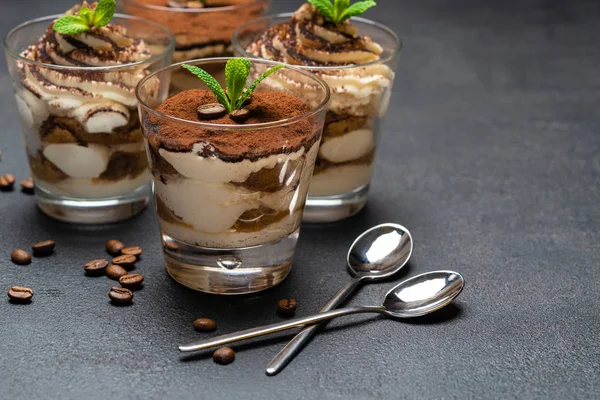 Postre tiramisú clásico en una taza de vidrio sobre fondo de hormigón oscuro —  Fotos de Stock