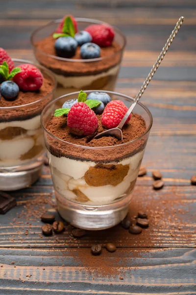 Klassisches Tiramisu-Dessert mit Blaubeeren und Erdbeeren in einer Glasschale auf Holzgrund — Stockfoto