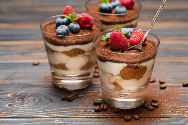 Classic tiramisu dessert with blueberries and strawberries in a glass cup on wooden background — Stock Photo, Image