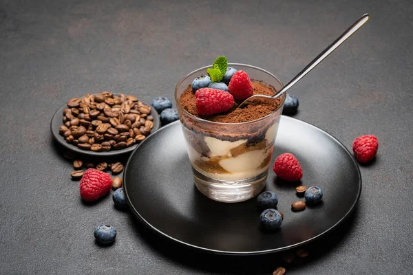 Класична десертна порція тірамісу з чорницею та малиною у склянці на кам'яній дошці на бетонному фоні — стокове фото