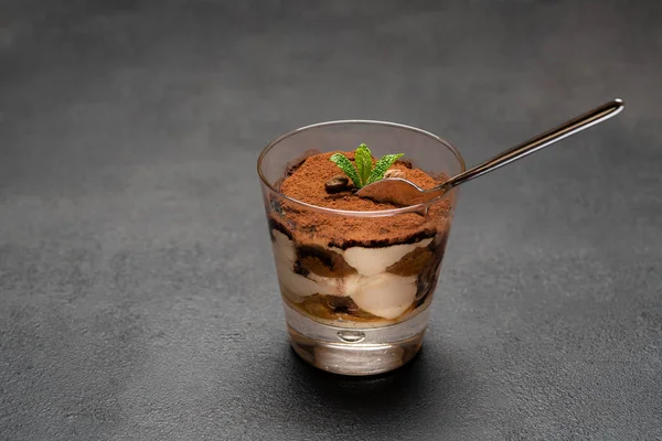 Porzione di dessert tiramisù classico in una tazza di vetro su sfondo di cemento scuro — Foto Stock