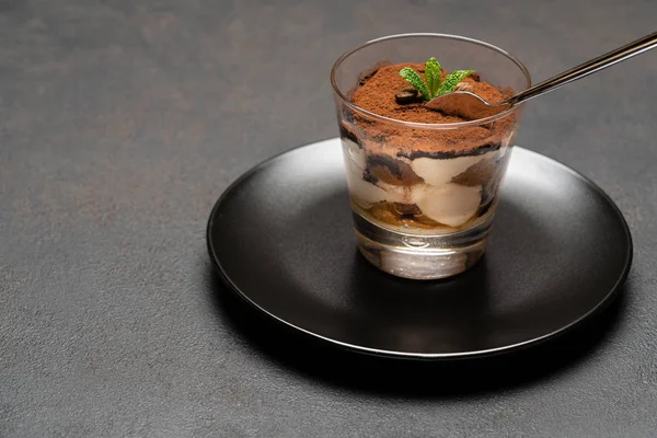 Porzione di dessert tiramisù classico in una tazza di vetro su sfondo di cemento scuro — Foto Stock