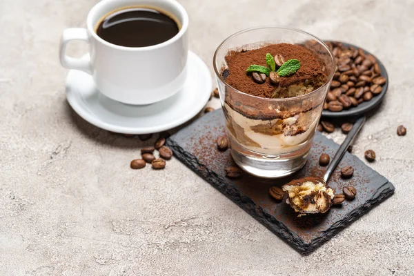 Чашка классического десерта тирамису в стеклянной чашке на каменной доске и кофе эспрессо на бетонном фоне — стоковое фото
