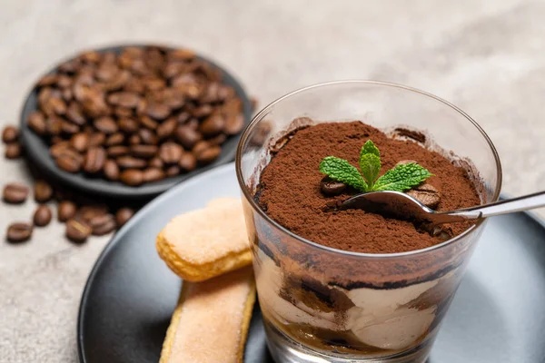 Porción de postre tiramisú clásico en una taza de vidrio sobre fondo de hormigón —  Fotos de Stock