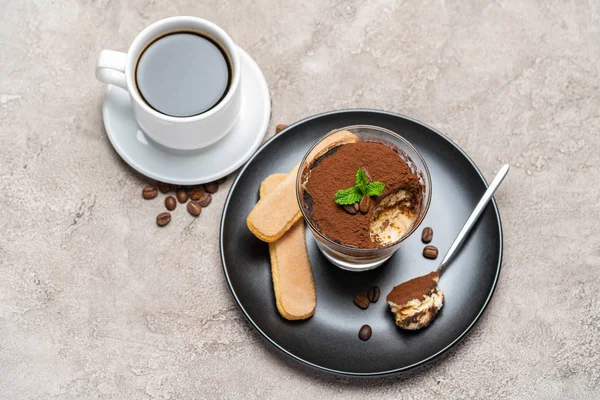 Portion de dessert tiramisu classique dans une tasse en verre et café expresso sur fond de béton — Photo