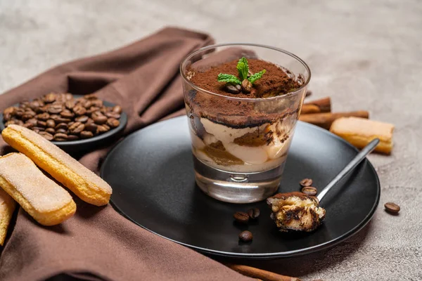 Porzione di dessert tiramisù classico in una tazza di vetro su sfondo di cemento — Foto Stock