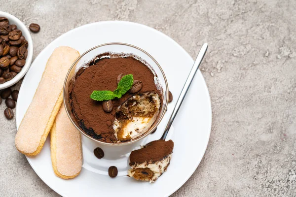Portie klassiek Tiramisu dessert in een glas, Savoiardi koekjes en kopje koffie op concrete achtergrond — Stockfoto