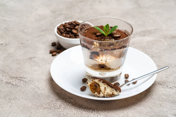 Porzione di dessert tiramisù classico in una tazza di vetro su sfondo di cemento — Foto Stock