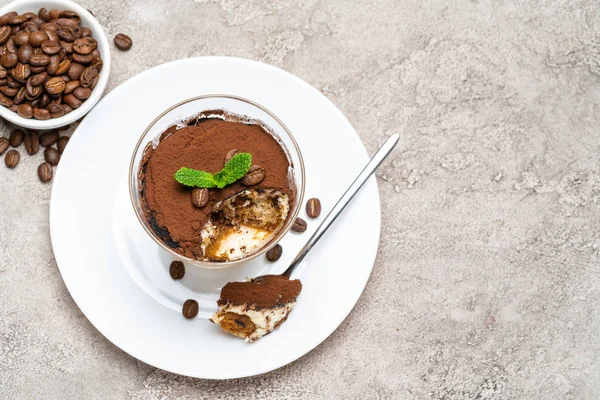 Portie klassiek Tiramisu dessert in een glazen beker op een betonnen achtergrond — Stockfoto