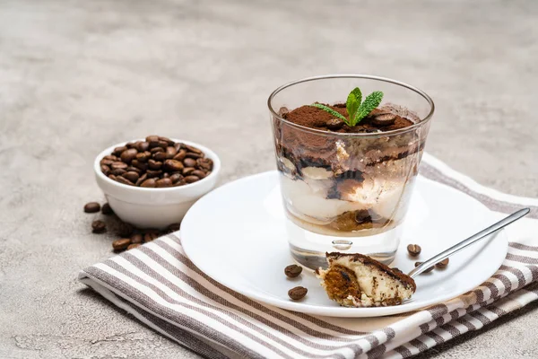 Porzione di dessert tiramisù classico in una tazza di vetro su sfondo di cemento — Foto Stock