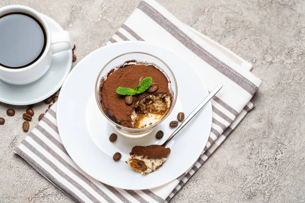 Portie klassiek Tiramisu dessert in een glas en kopje koffie op concrete achtergrond — Stockfoto