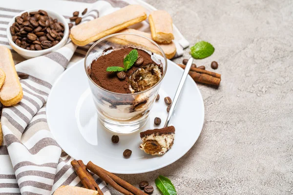 Portion klassisches Tiramisu-Dessert im Glas, savoiardi-Kekse und eine Tasse Kaffee auf Betongrund — Stockfoto
