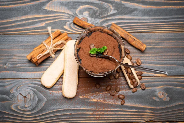 Porção de sobremesa tiramisu clássico em um copo e biscoitos savoiardi em fundo de madeira — Fotografia de Stock