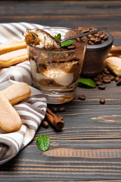 Porción de postre tiramisú clásico en un vaso y galletas savoiardi sobre fondo de madera — Foto de Stock