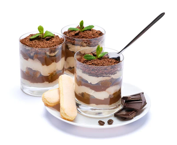 Postre tiramisú clásico en una taza de vidrio en el plato y trozos de chocolate sobre fondo blanco con camino de recorte — Foto de Stock